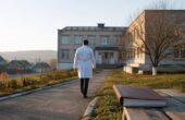 Верховный суд отменил взыскание 200 тысяч рублей с врача по программе «Земский доктор» Врач идёт к зданию районной больницы в сельской местности. Иллюстрация к новости о программе «Земский доктор» и судебном решении.